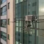 Drone DJI Matrice 350 RTK parado perto da fachada de vidro de um prédio residencial