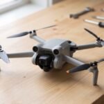 Drone pequeno com as hélices abertas sobre uma bancada de oficina, sob luz suave de janela