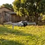Drone DJI Mini 4 Pro parado no ar sobre o quintal de uma chácara