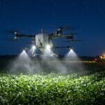 Drone DJI Agras T50 pulverizando uma lavoura de soja à noite