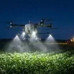 Drone DJI Agras T50 pulverizando uma lavoura de soja à noite